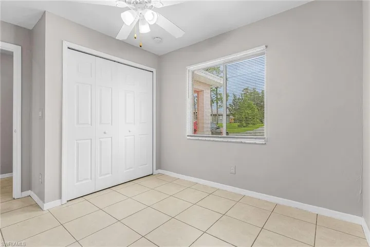 Unfurnished bedroom with light tile patterned floors, a closet, and a ceiling fan