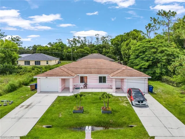 Ranch-style house with a front lawn, a shingled roof, a garage, and driveway