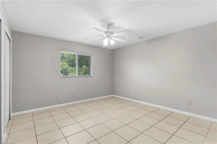Empty room with light tile patterned flooring and ceiling fan