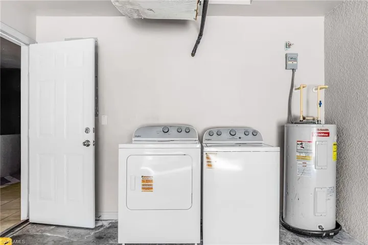 Washroom featuring electric water heater and independent washer and dryer