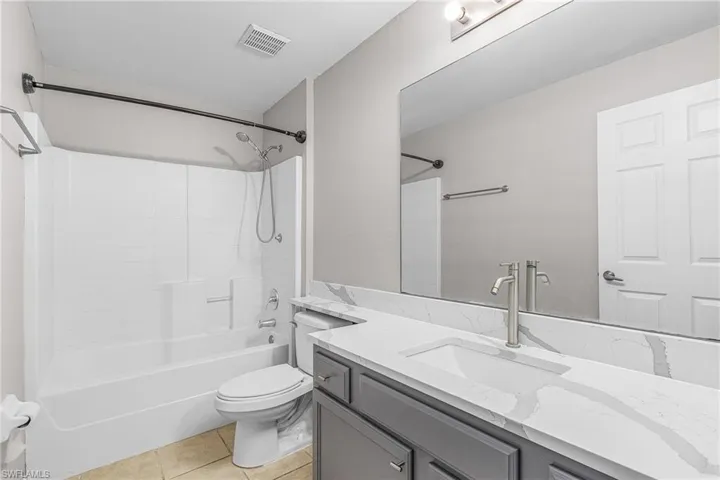 Bathroom featuring light tile patterned floors, vanity, and washtub / shower combination