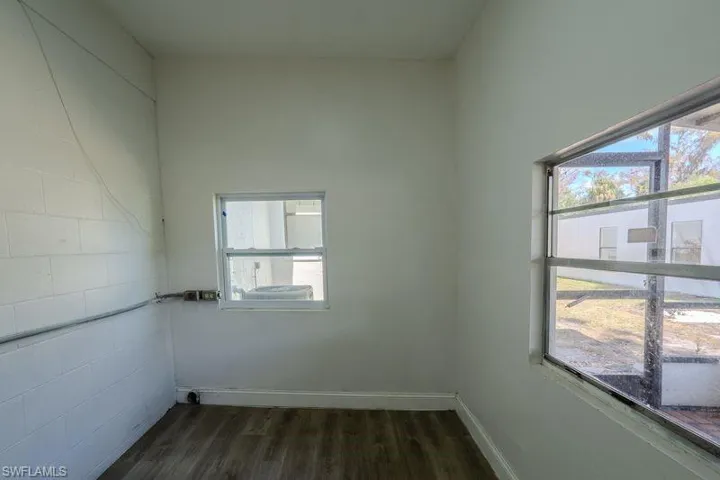 Spare room featuring dark wood-type flooring and baseboards