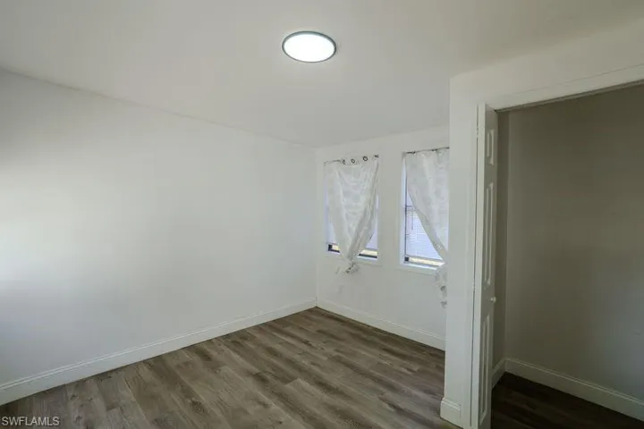 Empty room with dark wood-style floors and baseboards