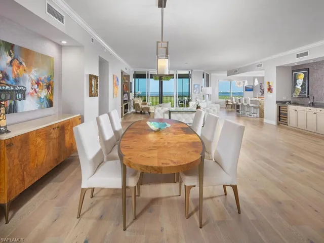 Dining area featuring light hardwood / wood-style floors, crown molding, and wine cooler