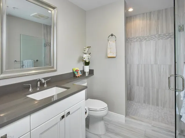 Bathroom featuring hardwood / wood-style flooring, vanity, toilet, and tiled shower