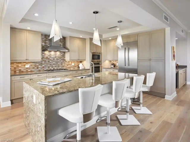 Kitchen with an island with sink, light hardwood / wood-style floors, built in appliances, and sink