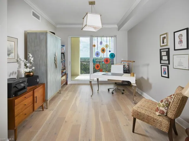 Office space with light hardwood / wood-style floors and crown molding
