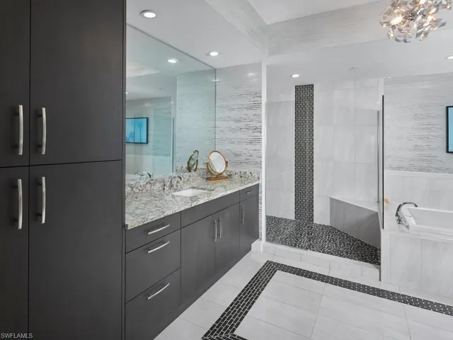 Bathroom featuring tile patterned flooring, shower with separate bathtub, vanity, and an inviting chandelier
