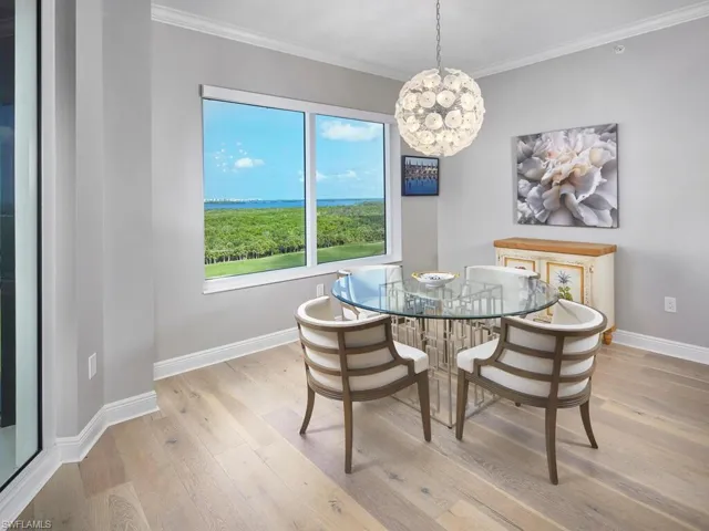 Dining room with a notable chandelier, ornamental molding, and light hardwood / wood-style flooring