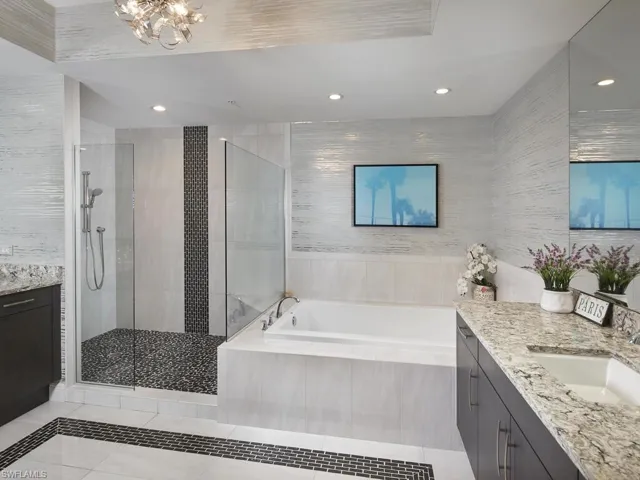 Bathroom featuring tile walls, tile patterned flooring, shower with separate bathtub, and vanity