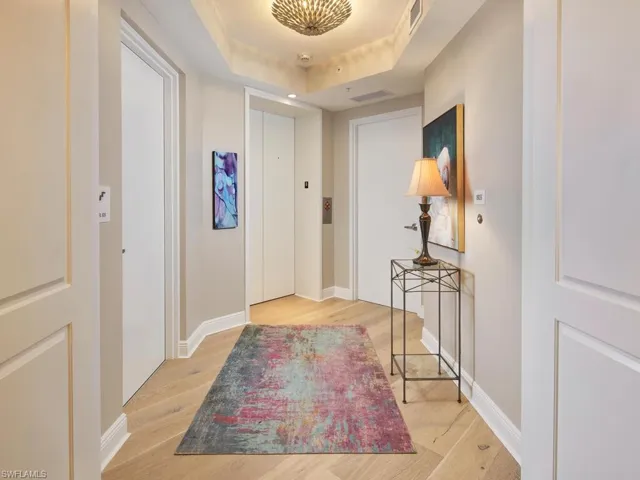 Hallway featuring a raised ceiling and light hardwood / wood-style flooring