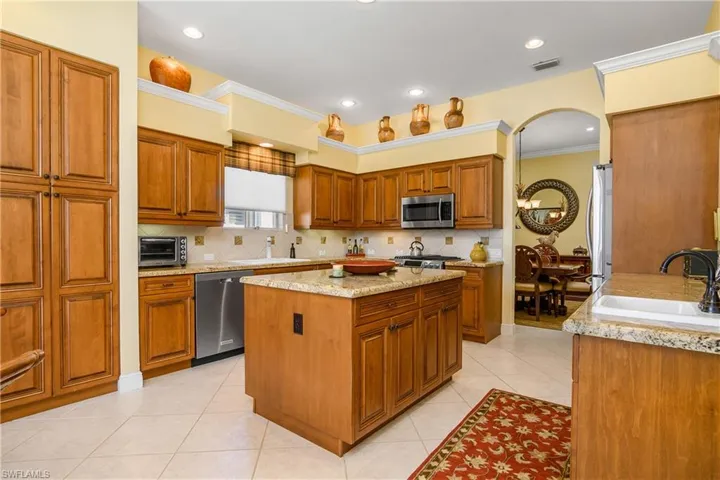 Large kitchen with stainless steel appliances, natural gas stove, granite countertops, 2 door custom pantry with slide out drawers, double sink and additional bar sink to right. Center island, plenty of storage cabinetry.