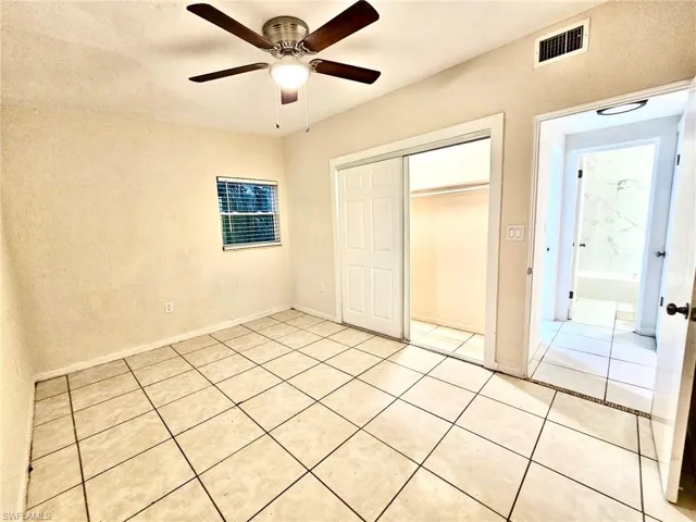 Unfurnished bedroom with a closet, light tile patterned floors, and a ceiling fan