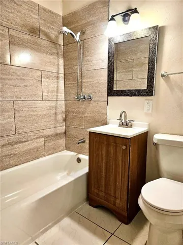 Bathroom with vanity, shower / bathtub combination, and a textured wall