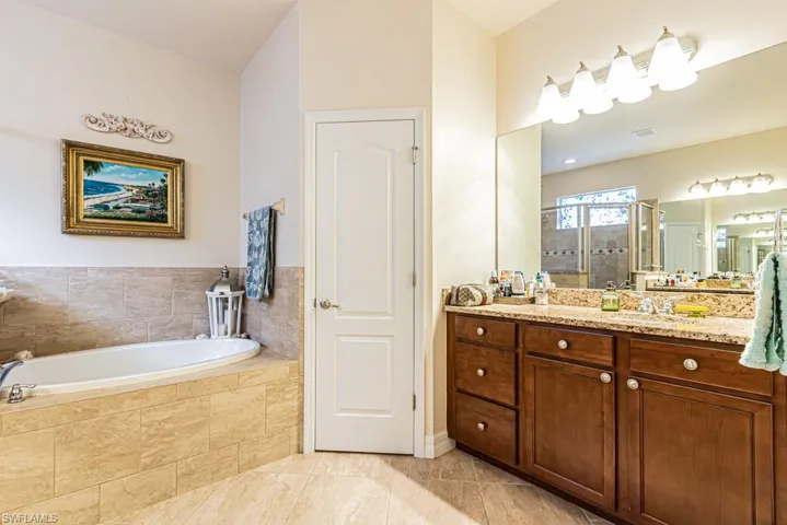 Bathroom with vanity, a stall shower, a garden tub, and light tile patterned floors