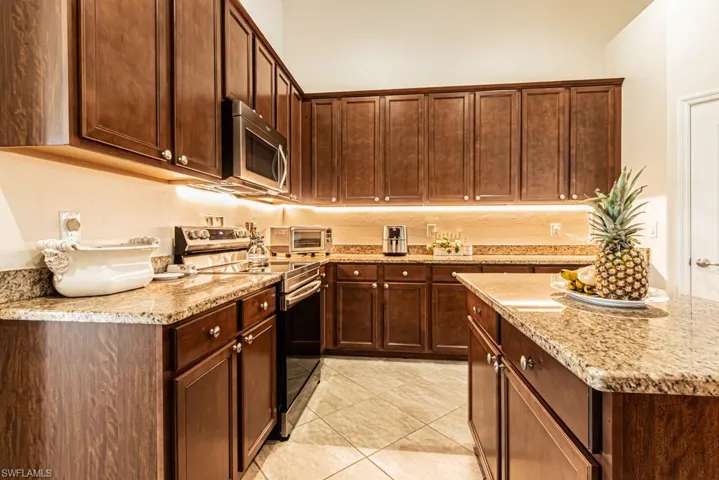 Kitchen with appliances with stainless steel finishes, light stone counters, and light tile patterned floors