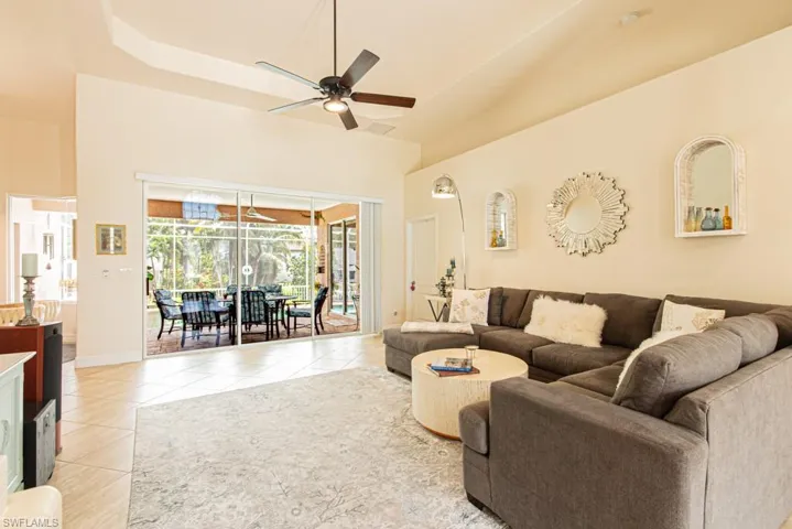Living room featuring ceiling fan, light tile patterned flooring, a raised ceiling, and a sunroom