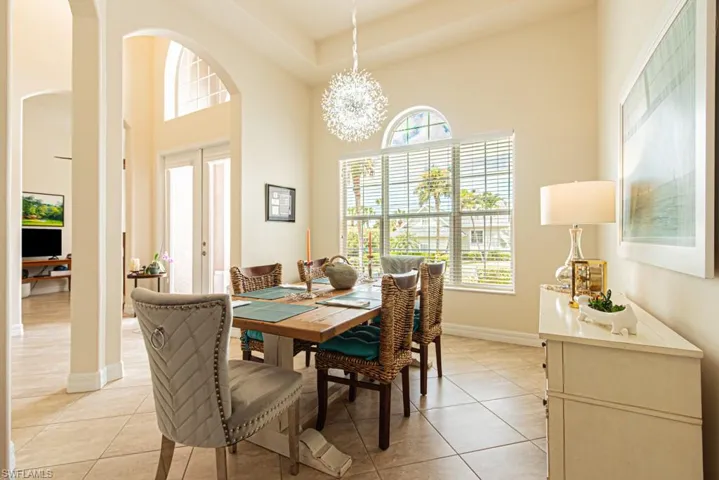 Dining room with arched walkways, light tile patterned floors, french doors, a chandelier, and a high ceiling