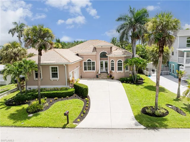 Mediterranean / Spanish house with driveway, stucco siding, a front yard, a tiled roof and a 3-car garage