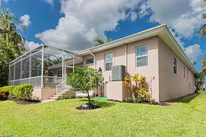 Rear view of house featuring a sunroom, stucco siding, glass enclosure, a yard, and stairs