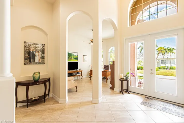 Foyer featuring arched walkways, french doors, healthy amount of natural light, and a high ceiling