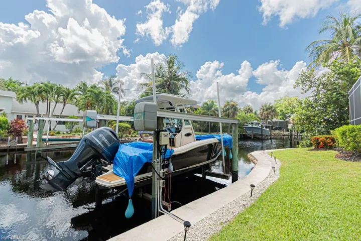 Dock with a water view, boat lift and a yard