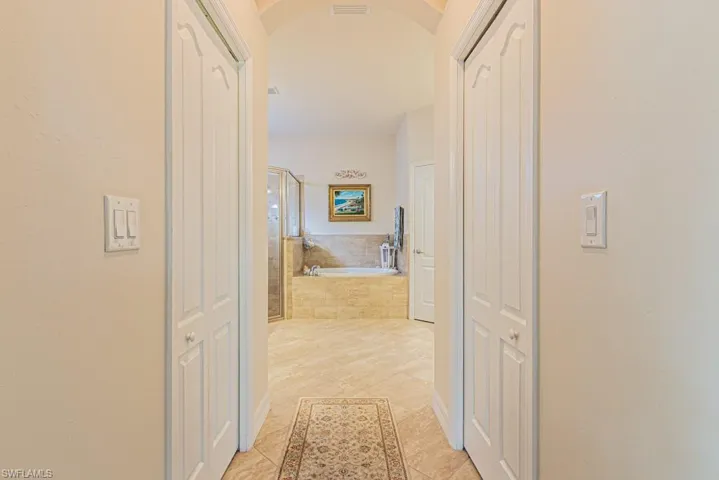 Hallway with arched walkways and light tile patterned floors