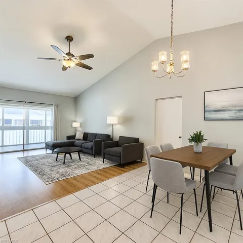 Dining room featuring a chandelier, light tile patterned floors, a ceiling fan, and high vaulted ceiling