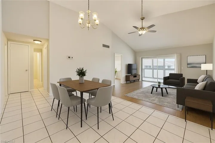 Dining space with high vaulted ceiling, a chandelier, light tile patterned flooring, and a ceiling fan