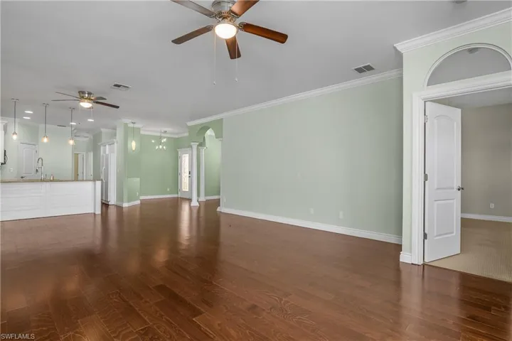 living room with ceiling fan, ornamental molding,  wood-style floors, and arched walkways