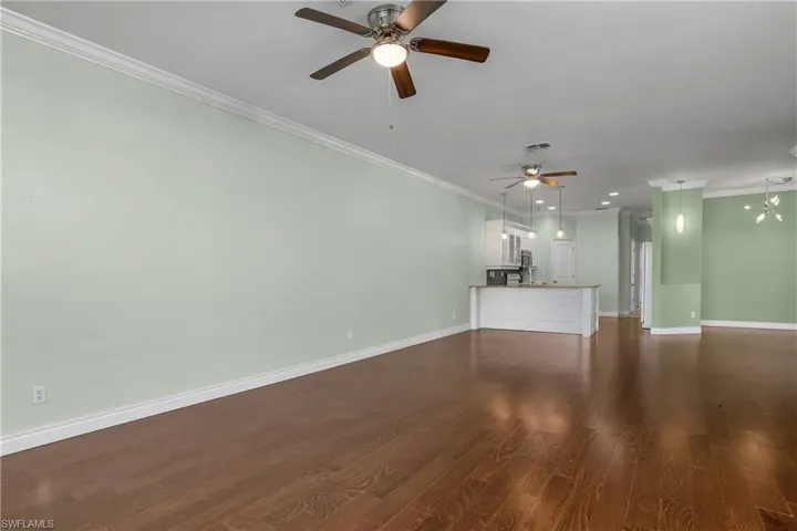 living room with a ceiling fan, crown molding, and wood-style flooring