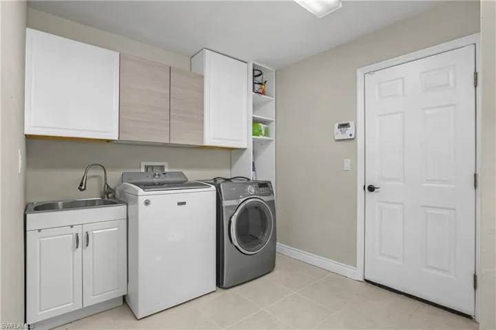 Laundry room with cabinet space, separate washer and dryer, and light tile patterned flooring