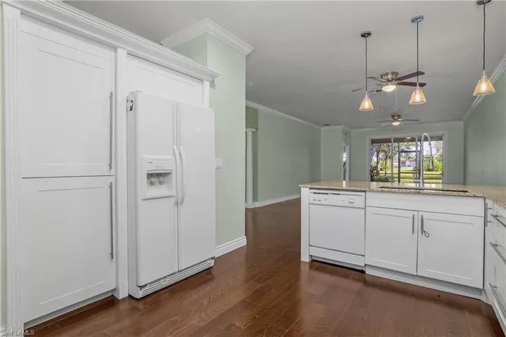 Kitchen with white appliances, decorative light fixtures, a ceiling fan, white cabinets, and ornamental molding