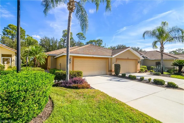 View of front of property with concrete driveway, stucco siding, a tile roof, a garage, and a front lawn