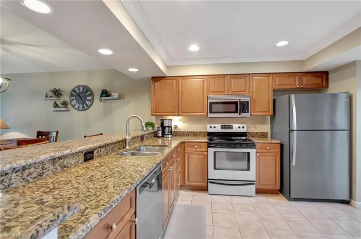 Kitchen with granite countertops, stainless steel appliances, and light tile flooring