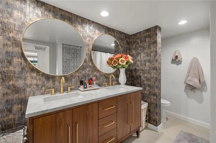 Bathroom featuring double vanity, recessed lighting, and backsplash