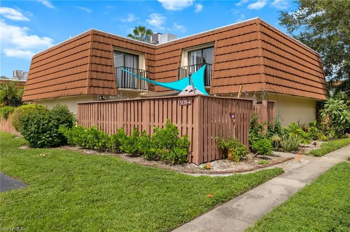 View of side of home with mansard roof and stucco siding