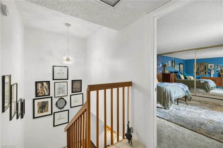 Stairway with a textured ceiling, a chandelier, and carpet flooring