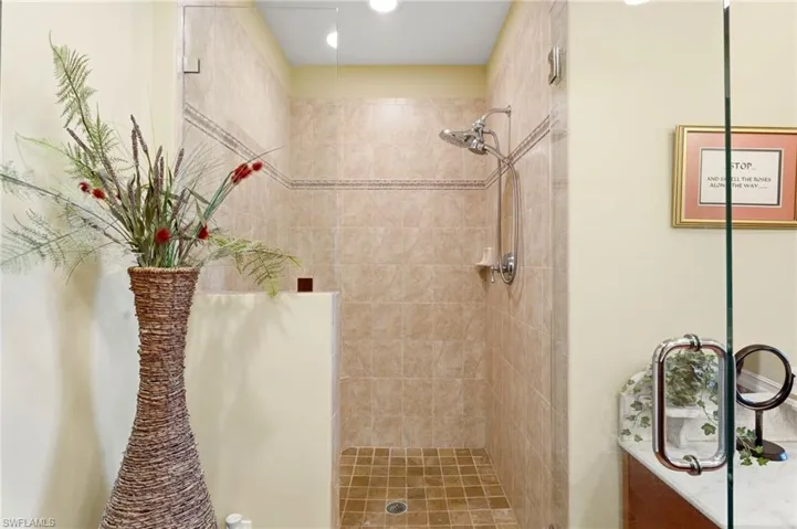 The primary walk-in shower features a sleek, seamless glass enclosure.