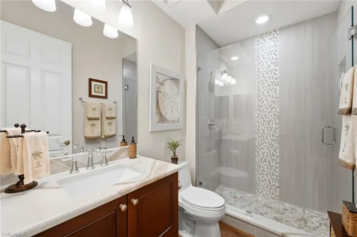 Redesigned 2nd full bath offers a walk in shower, stunning listello with floor to ceiling porcelain tile and a seamless glass enclosure. A beautiful quartz topped vanity. Stunning hardware!