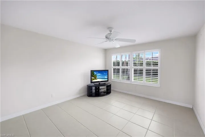 Recessed lighting, ceiling fan, neutral wall tones, large window with plantation shutters, and tile flooring