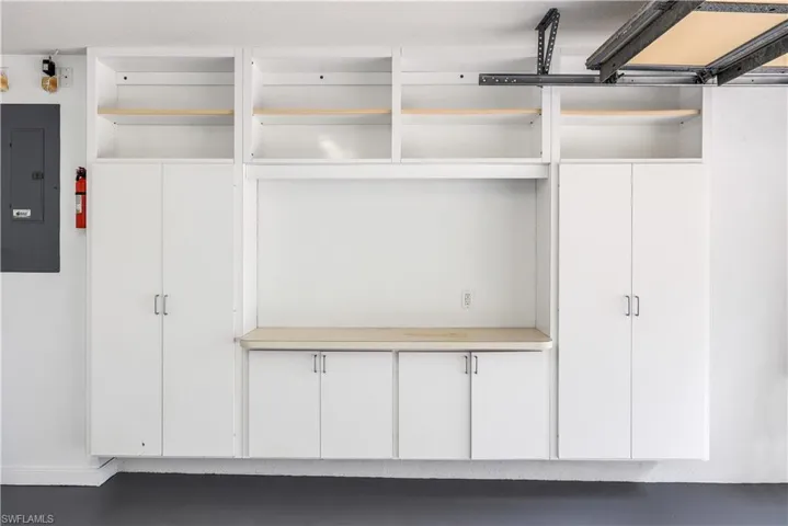 Built-in white cabinetry with brushed nickel hardware, open shelving, and a wood-finish countertop