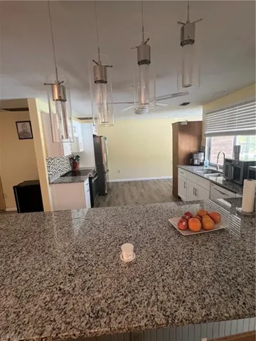 Kitchen with white cabinetry, refrigerator, hardwood / wood-style floors, pendant lighting, and sink