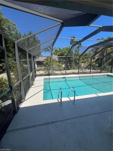 View of swimming pool with a patio and glass enclosure
