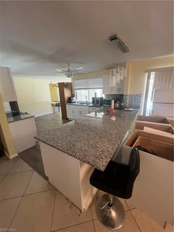 Kitchen with white cabinetry, kitchen peninsula, ceiling fan, and a kitchen breakfast bar