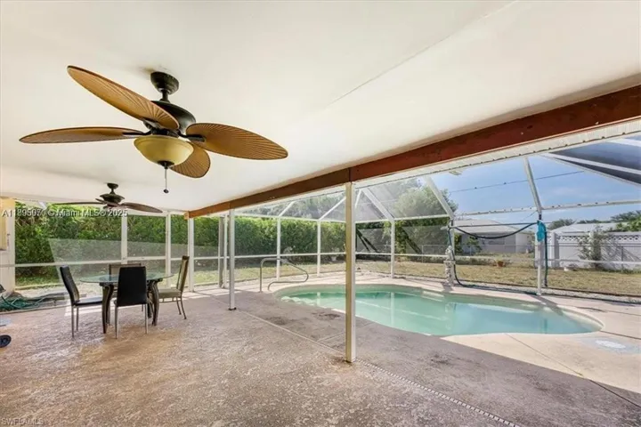 Outdoor pool featuring a sunroom, glass enclosure, a patio, and outdoor dining area