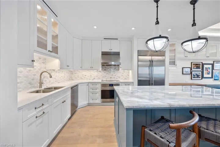 Kitchen featuring illuminated quartzite island countertop, stainless steel Wolf, Cove, and Sub-Zero appliances