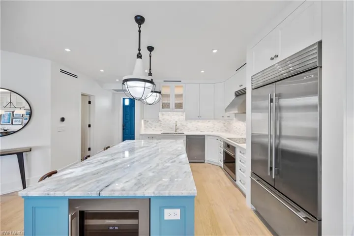 Kitchen featuring illuminated quartzite island countertop, stainless steel Wolf, Cove, and Sub-Zero appliances