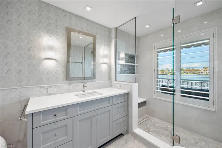 Primary suite bath featuring vanity and walk-in shower with bay view