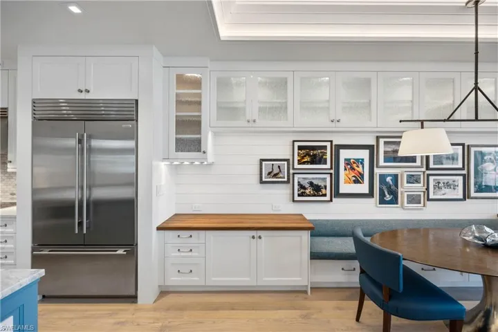 Kitchen featuring stainless steel Sub-Zero refrigerator, white cabinetry, glass insert cabinets, and under cabinet lighting